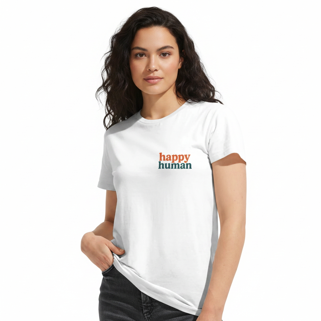 A woman wearing an Aretis white short-sleeve crewneck t-shirt with 'happy human' printed on the chest in orange and dark green, paired with black jeans, against a plain white background.
