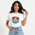 Woman wearing a white t-shirt with a colourful palm tree design on a plain background